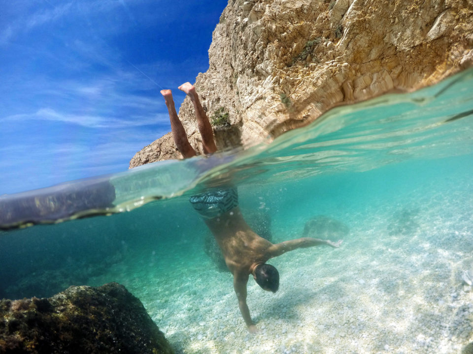 Man in boardshorts doing handstands in the sea over under photo