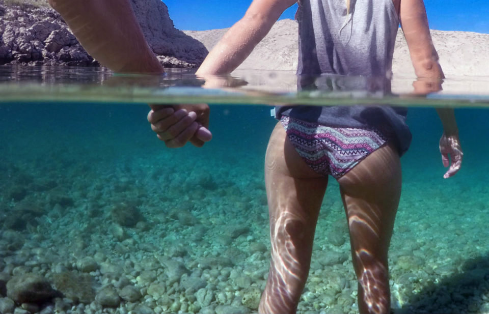 Girl holding boys hand in warm sea over under photo