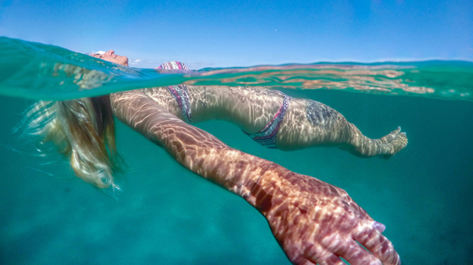 Girl in a bikini floating in the sea over under photo